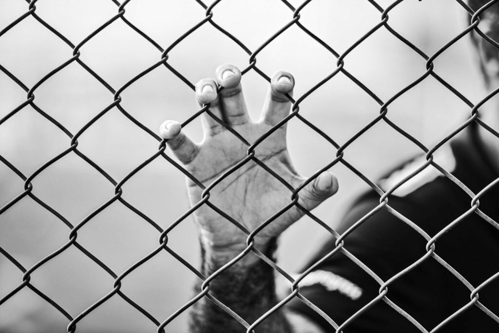 man holding chain-link fence